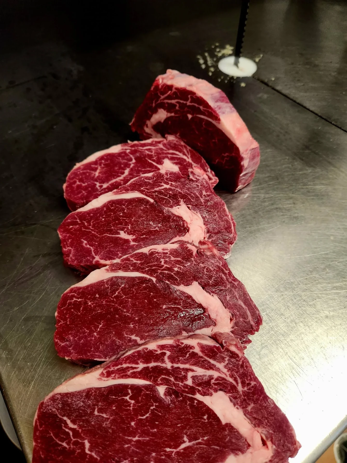 Heavily marbled ribeye steaks on a butcher's steel bench at Bianchi's Butchery Cooktown